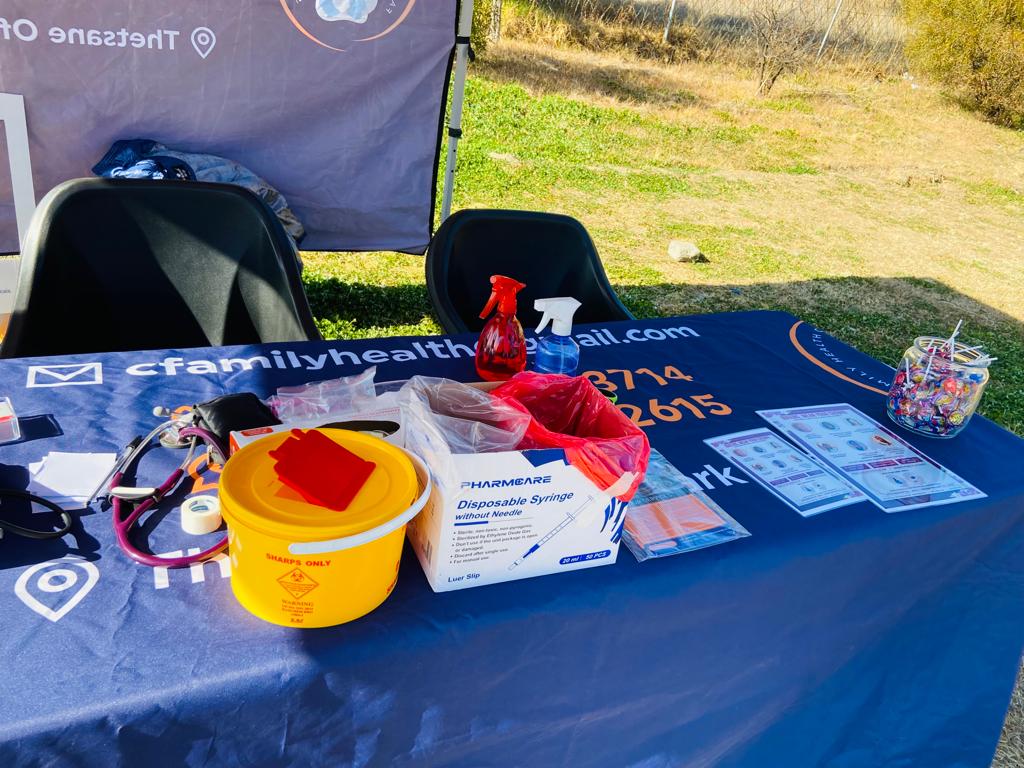 A Family Health Clinic outreach table set up outdoors with clinical supplies and branded signage